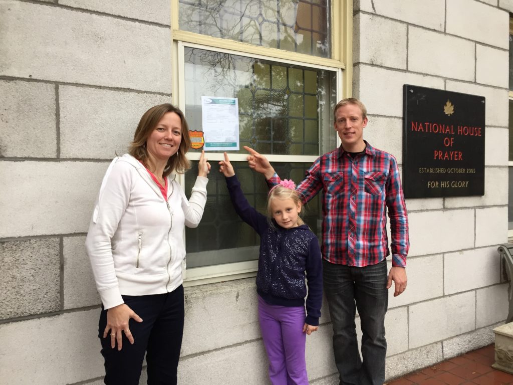 Ken, Deb, and Olivia point to the building permit. 
