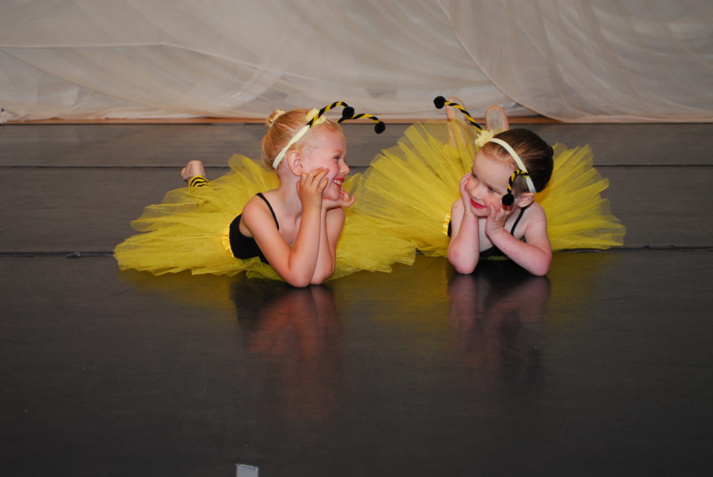 Two young dancers smile at each other. 