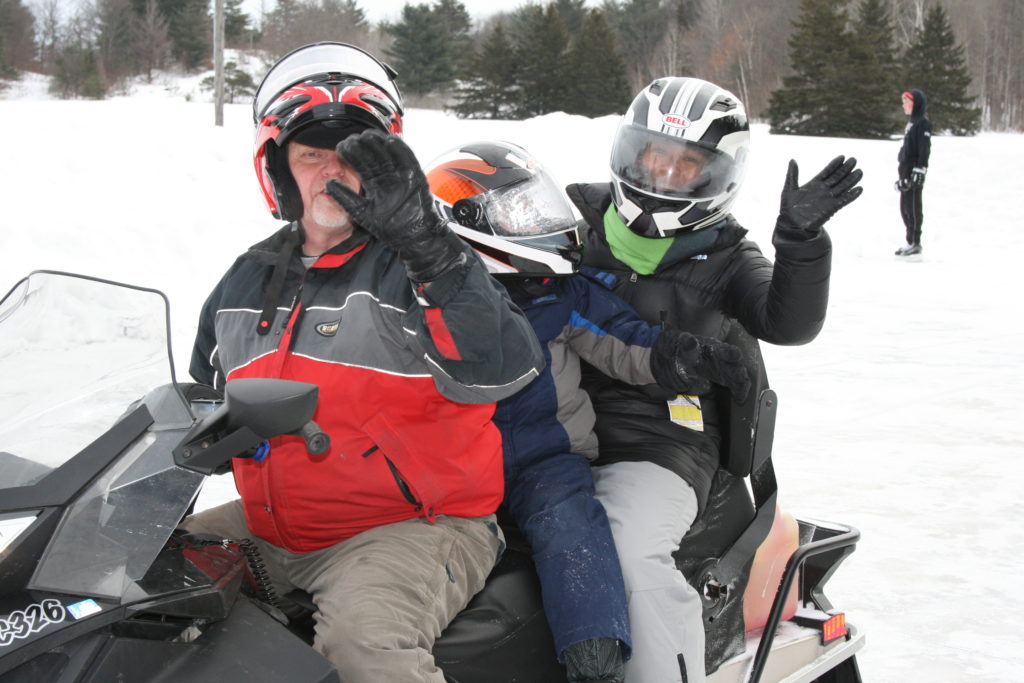 Three people ride a snowmobile. 