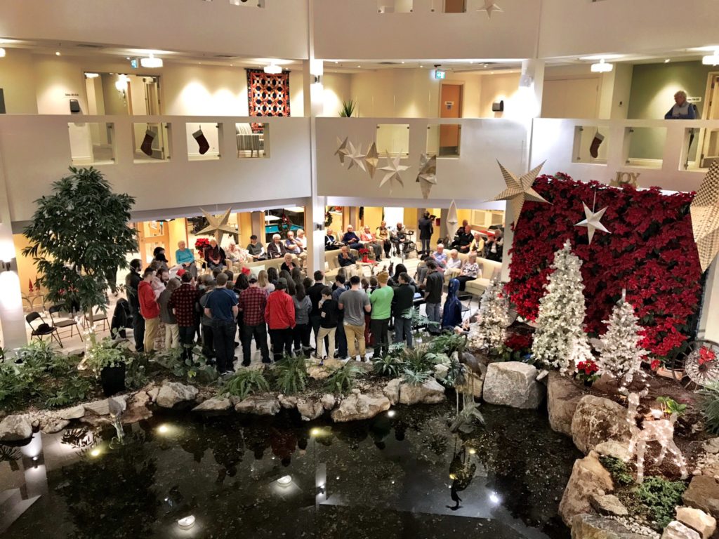 A group of youth sing carols with seniors. 